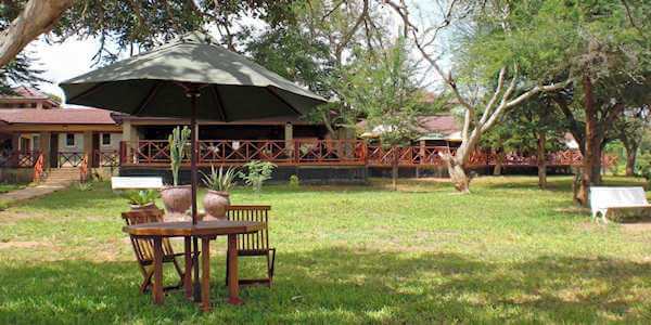 Ashnil Aruba Lodge uitzicht vanuit de tent met diverse zithoeken op de lounge en het restaurant met groot veranda dek. Tsavo Oost Nationaal Park in Kenia