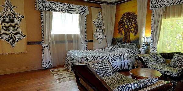 Accommodatie inrichting de 'Zebra room' luxe suite en over 100 jaar oud met en-suite een badkamer. Lake Nakuru Lodge accommodatie inrichting de 'zebra room' luxe suite en over 100 jaar oud met en-suite een badkamer. Nakuru Nationaal Park in Kenia