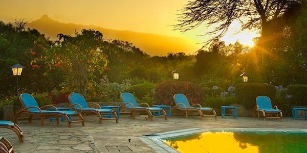 Zwembad met zonneterras bij het restaurant waar de lunch geserveerd word en uitzicht op de Mount Kenya. Zwembad met zonneterras bij het restaurant waar de lunch geserveerd word en uitzicht op de Mount Kenya, accommodatie Mount Kenya Nationaal Park in Kenia